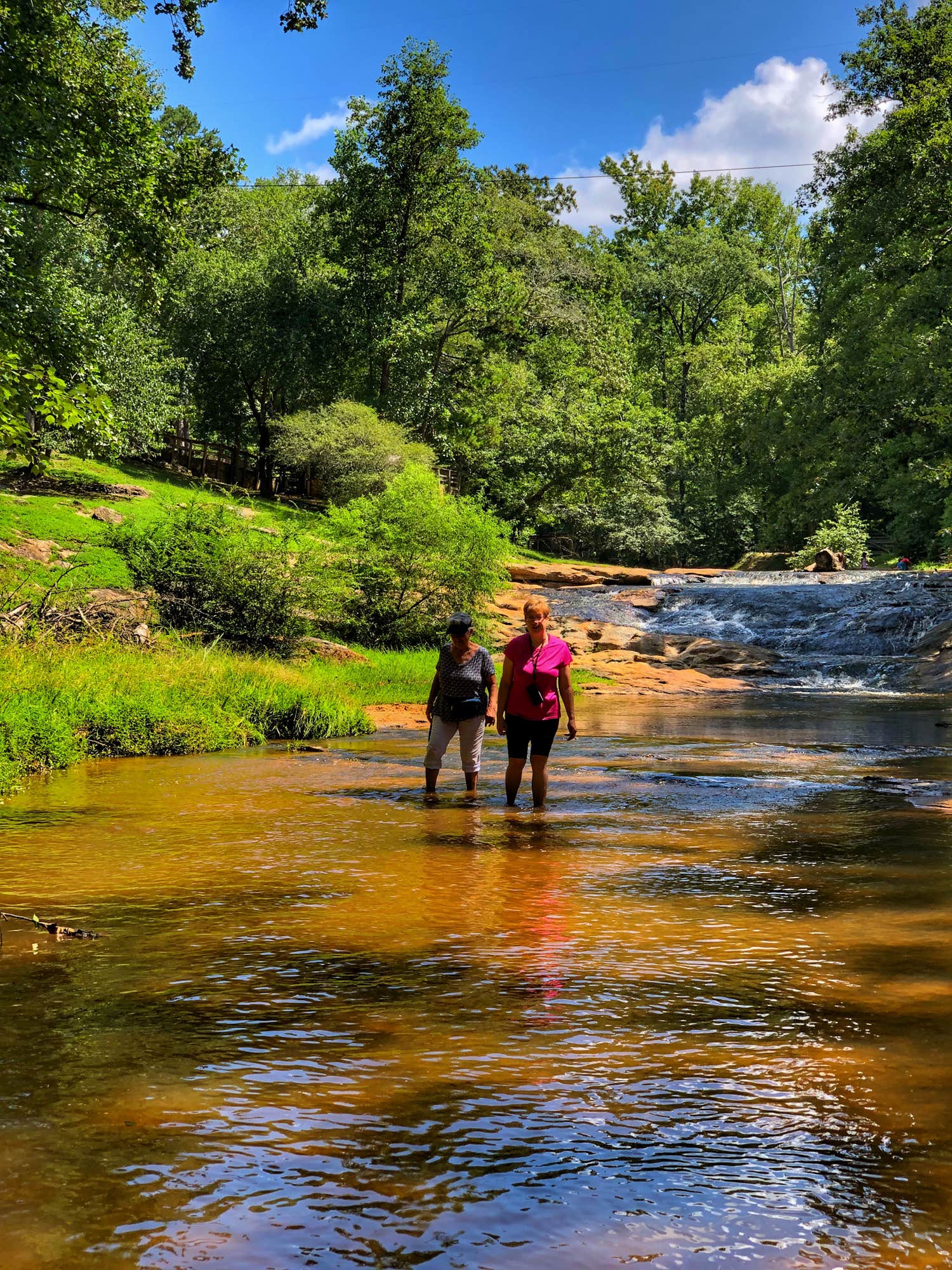 two campers wade in a shallow river in victoria bryant state park