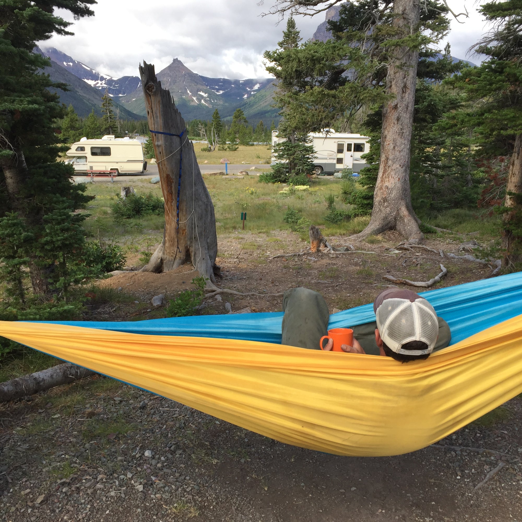 Person sitting in a yellow hammock at an RV site