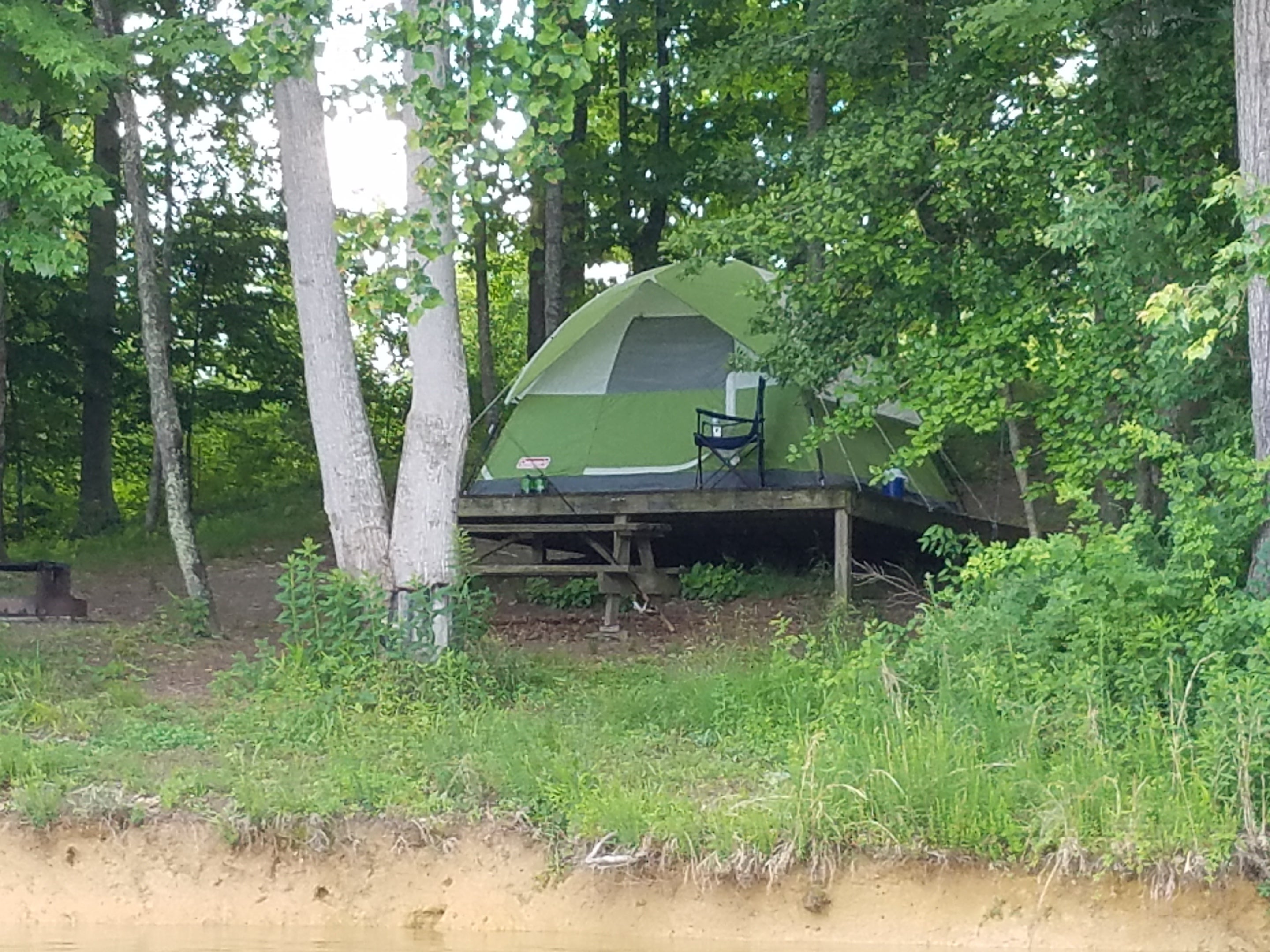 Tent camping on wooden platforms at lake's edge.