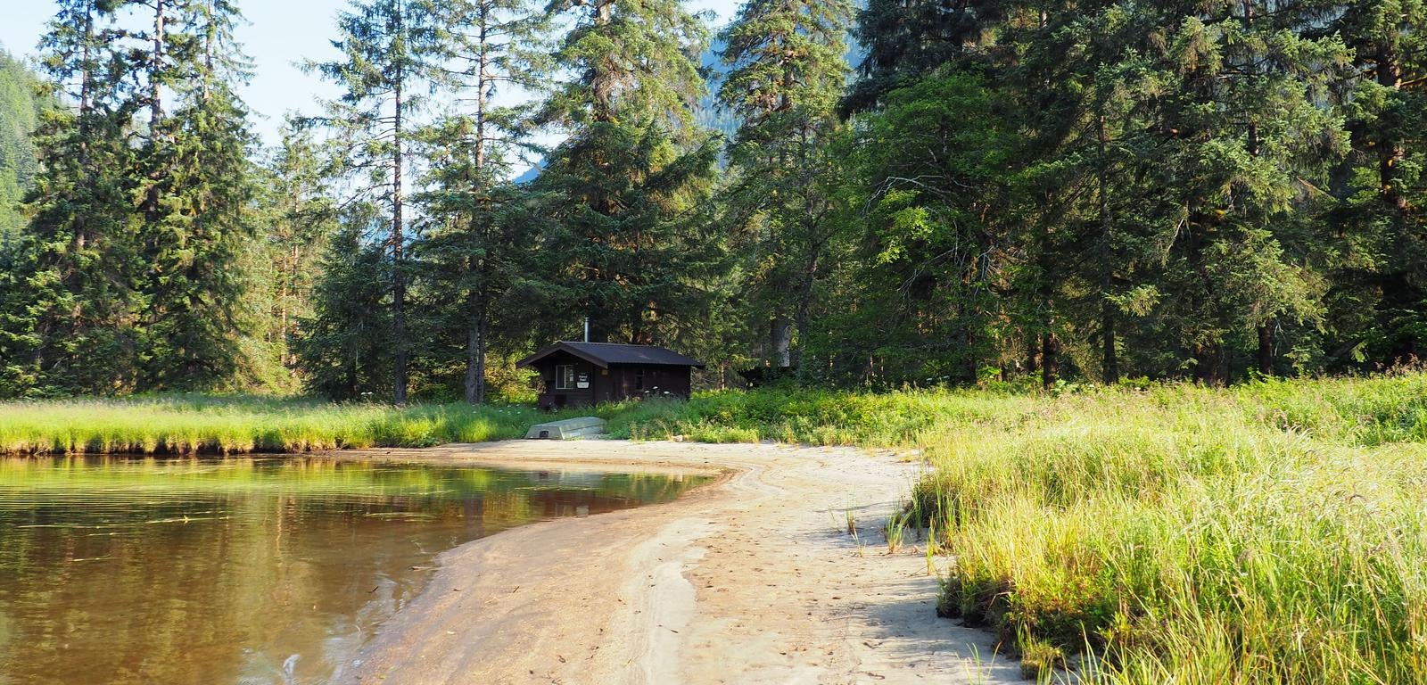 Marten Lake Cabin with trees surrounding it and water in front with a small boat and tall grass



Marten Lake Cabin exterior scenery

Credit: USFS