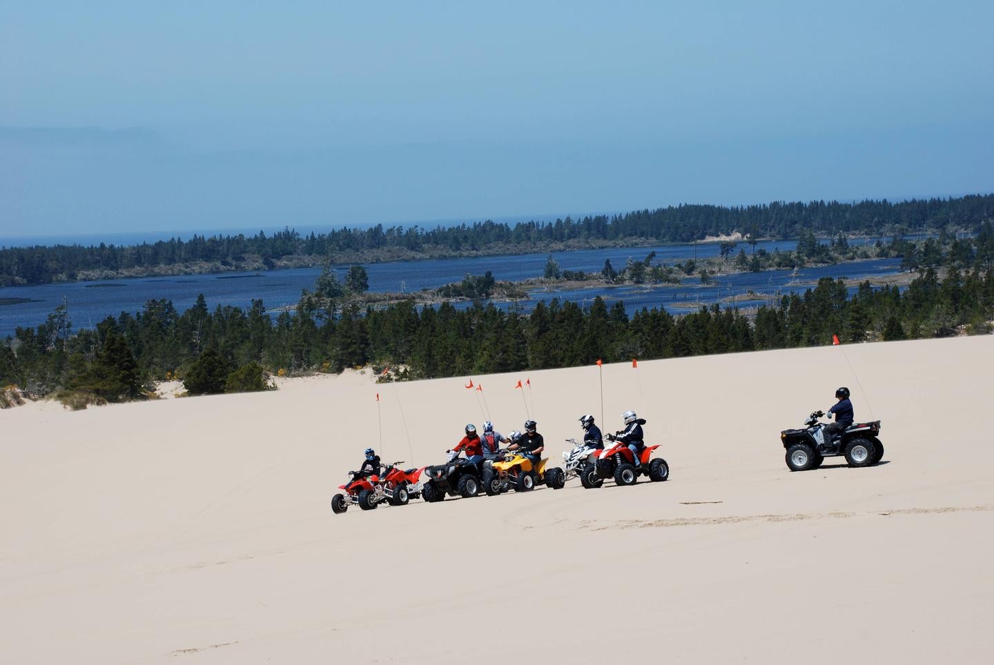 Off road vehicles on flat expanse of sand in front of blue lake ringed by conifer trees.



The dunes near Horsfall Campground

Credit: USFS