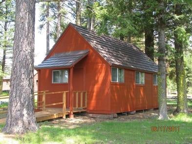 Small, orange-red cabin with ramp to front door in sun dappled conifer forest.



Summit guard station bunkhouse

Credit: USFS
