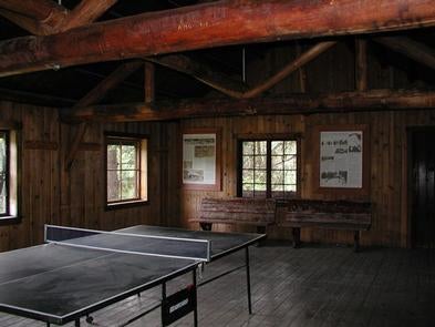 Ping-pong table in dimly lit large room with log rafters and benches.



Ping-Pong table in American Ridge Lodge 

Credit: USFS