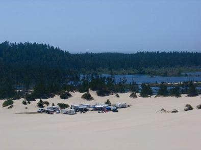 Group of trailers and trucks on a large expanse of sand near a conifer encircled lake under a blue sky.



Horsfall sand camping

Credit: USFS