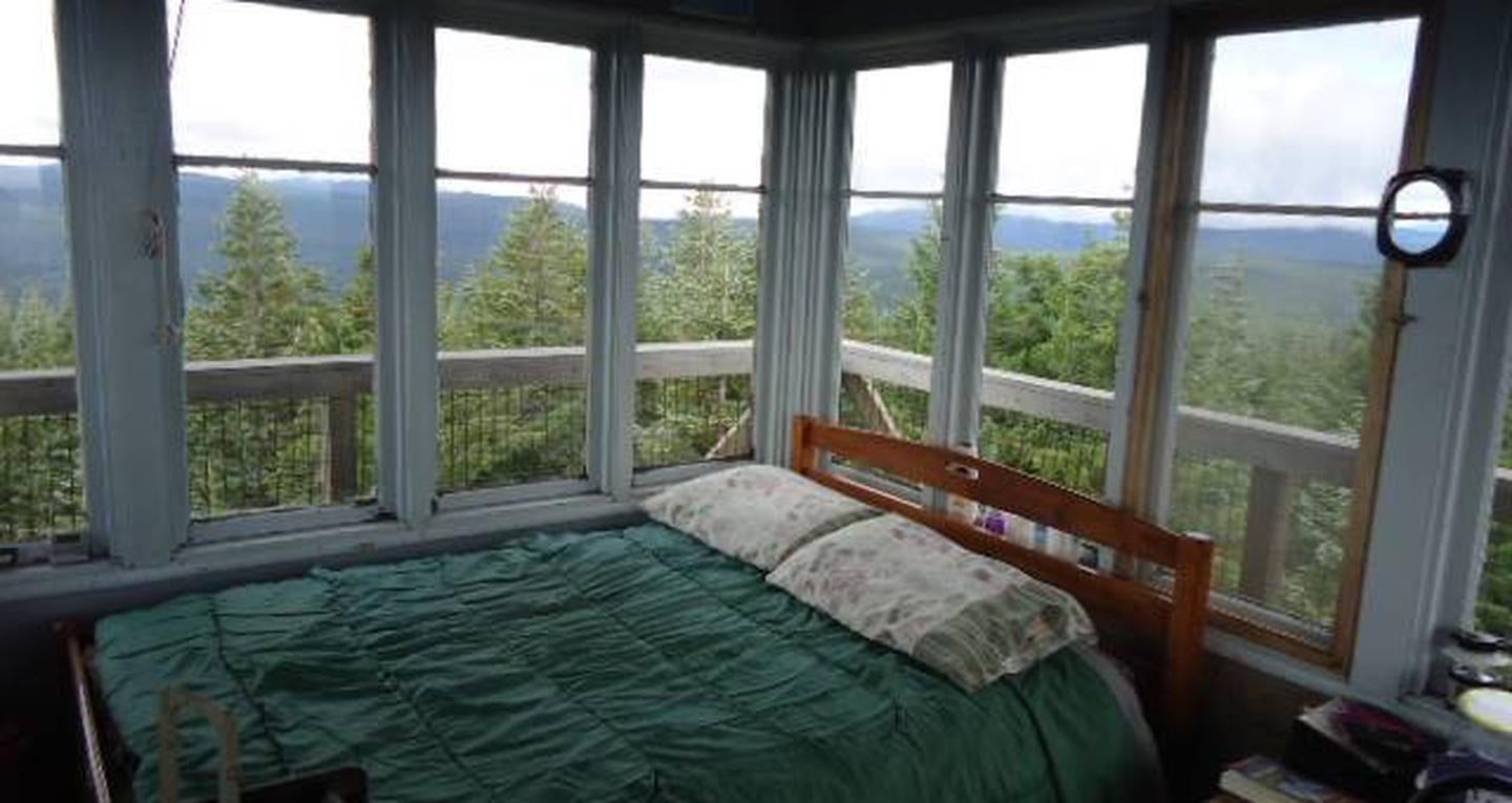 Full size bed in front of 8 window with view of mountains and trees beyond.



Clear Lake Lookout sleeping area.

Credit: USFS