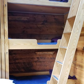 Triple decker bunks with 3 wool blankets and a pillow; small shelves for personal items, hooks for your pack and jackets