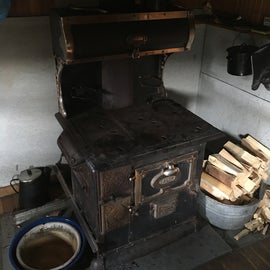 The wood stove. Some basins and cooking tools nearby. 