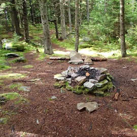 The summit campsite areas have been widely used and often have wonderful creature comforts like the stone seats in the background beyond the fire pit.