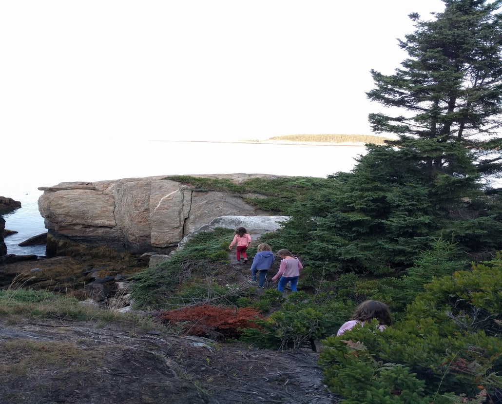 Four young girls walk together on a hike on Hermit Island, Maine.