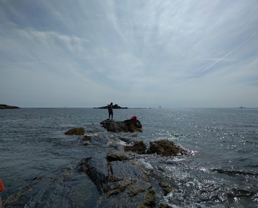 A man looks down from a rocky outcropping in the Atlantic Ocean, off the coast of Hermit Island, Maine
