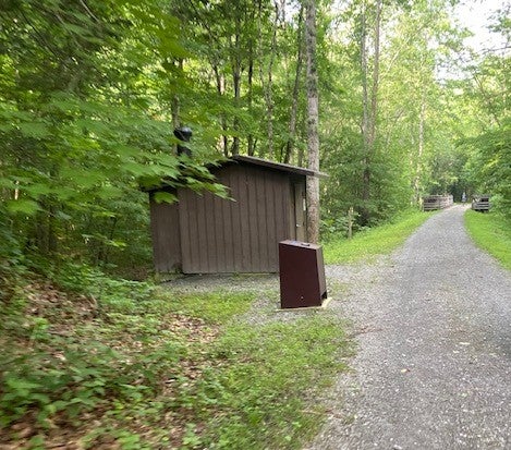 Pit latrine and bear-proof trash receptacle across the Trail from the tent pad campsite