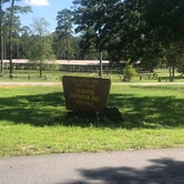 Entrance sign with horse corrals in background.