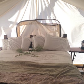 A different tent option with a king bed, couch, and bathroom/shower inside the tent.